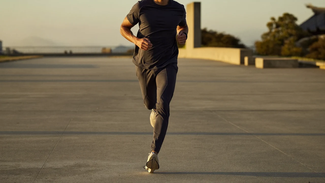 Sportlerin in schlichter Trainingskleidung läuft frühmorgens über eine leere Betonpromenade