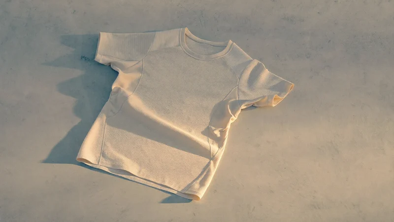 Leichtes Laufshirt aus Mesh-Gestrick flach auf hellem Beton, Ansicht von oben